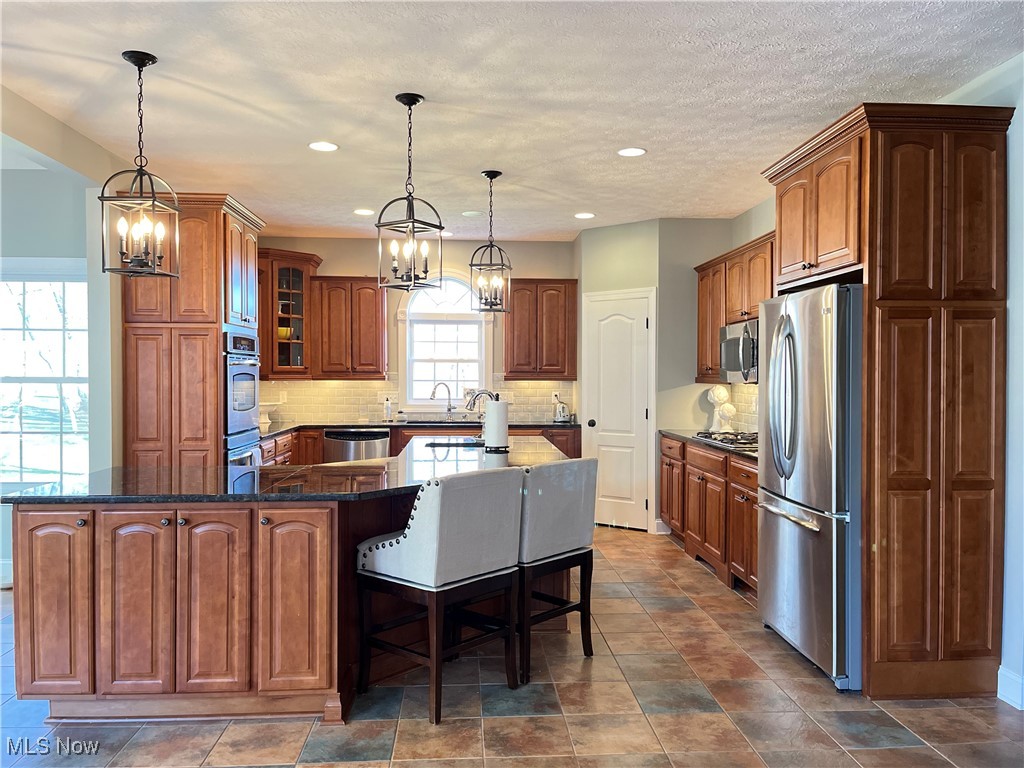 4679 Paxton Road Akron, OH 44321 - Photo 21 of 46 Kitchen with stainless steel appliances, a chandelier, a spacious island, decorative backsplash, and recessed lighting