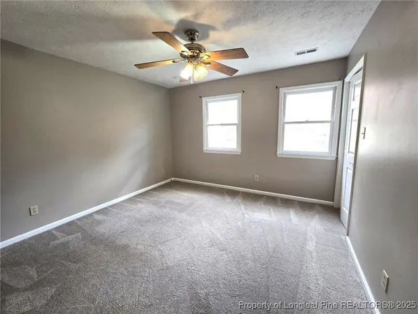 an empty room with windows and chandelier fan