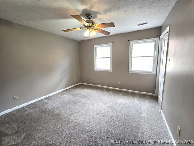 an empty room with windows and chandelier fan