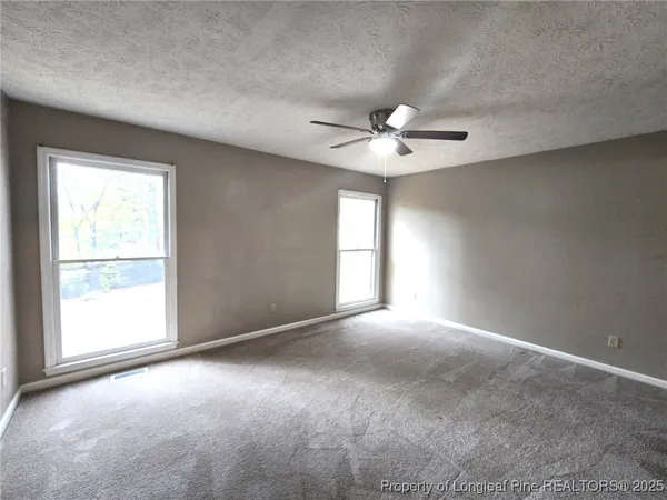 an empty room with windows and chandelier fan