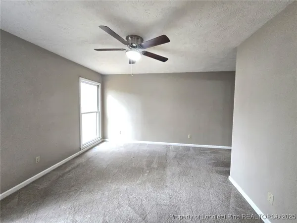 an empty room with windows and fan