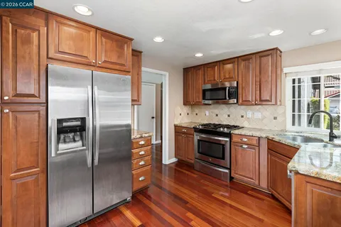 a kitchen with granite countertop a refrigerator stove and microwave