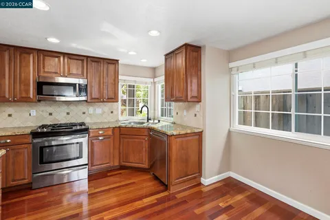 a kitchen with stainless steel appliances granite countertop a stove a sink and a microwave