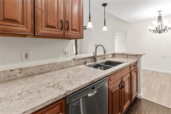 a kitchen with stainless steel appliances granite countertop a sink a stove and a wooden floors