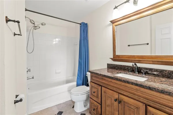 a bathroom with a granite countertop sink a toilet and shower