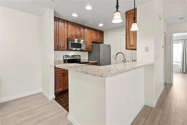 a kitchen with stainless steel appliances granite countertop a sink a stove a refrigerator cabinets and a wooden floor