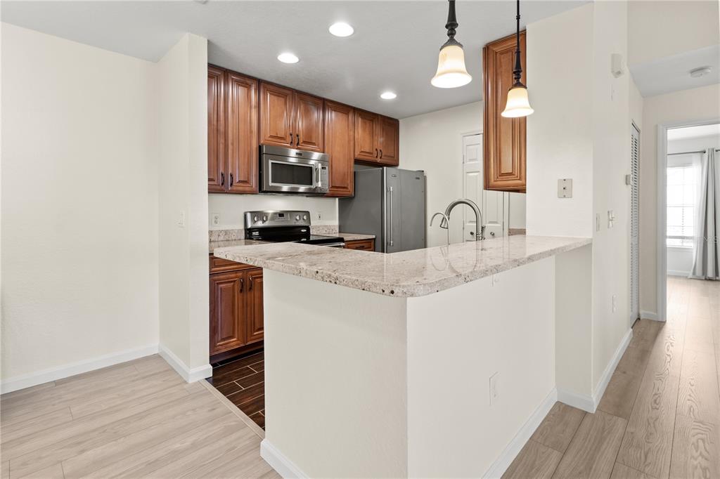 8911 Manor Loop, Unit 208 Lakewood Ranch, FL 34202 - Photo 23 of 49 a kitchen with stainless steel appliances granite countertop a sink a stove a refrigerator cabinets and a wooden floor