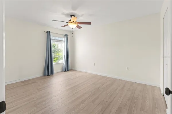 a view of an empty room with wooden floor and a window