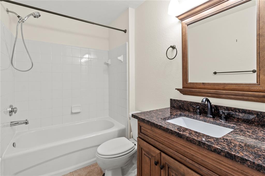 8911 Manor Loop, Unit 208 Lakewood Ranch, FL 34202 - Photo 41 of 49 a bathroom with a granite countertop sink a toilet and a mirror