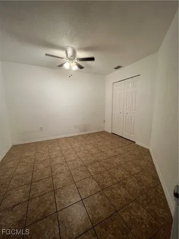 a view of an empty room and chandelier fan