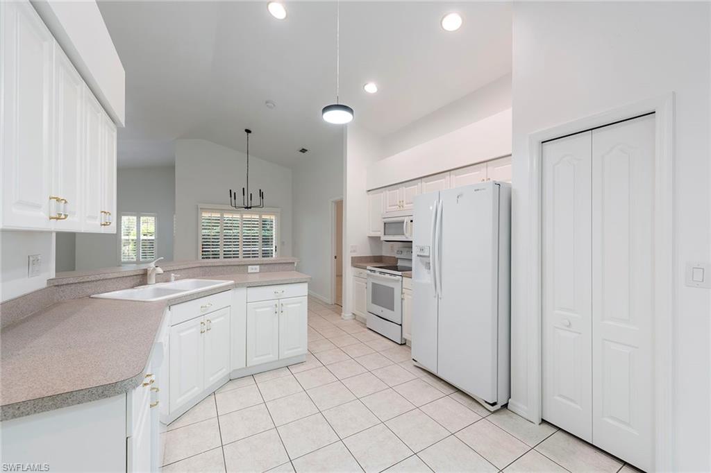 21695 Brixham Run Loop Estero, FL 33928 - Photo 10 of 32 a kitchen with white cabinets and white appliances