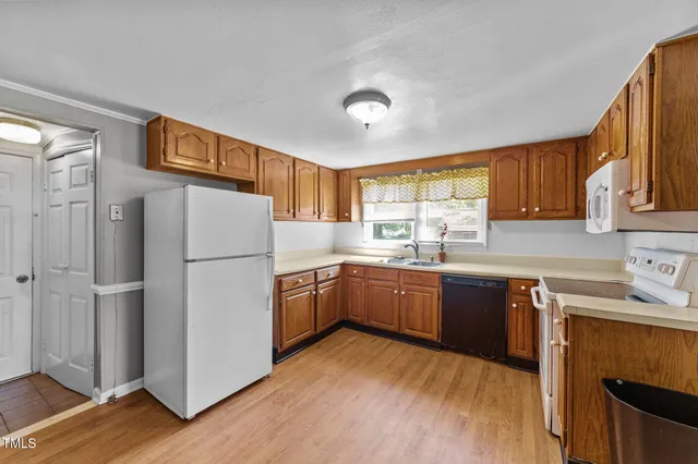 a kitchen with stainless steel appliances granite countertop a refrigerator a sink dishwasher a stove with wooden cabinets and floor