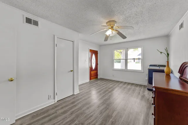 a view of an empty room with window and wooden floor