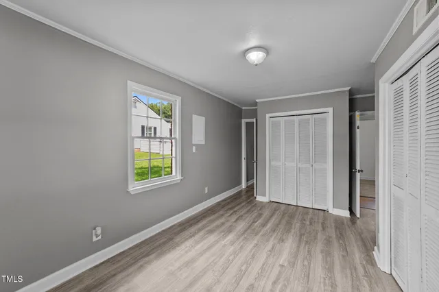 a view of an empty room with wooden floor and a window