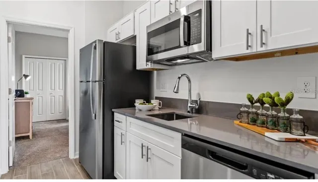 a kitchen with stainless steel appliances granite countertop a sink a refrigerator and a granite counter tops