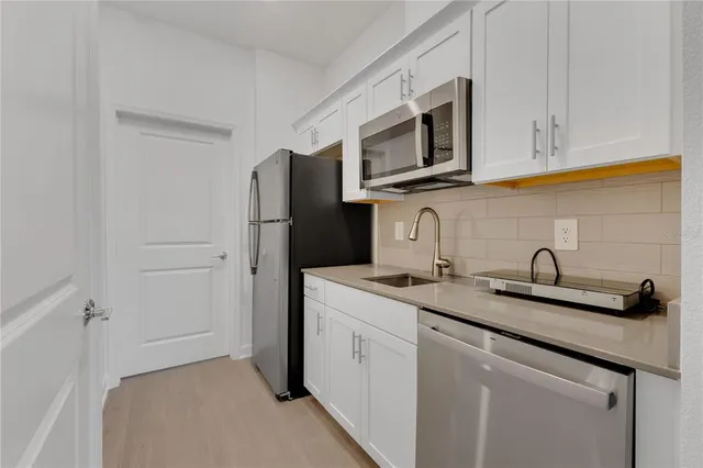 a kitchen with stainless steel appliances granite countertop white cabinets a microwave a sink and dishwasher