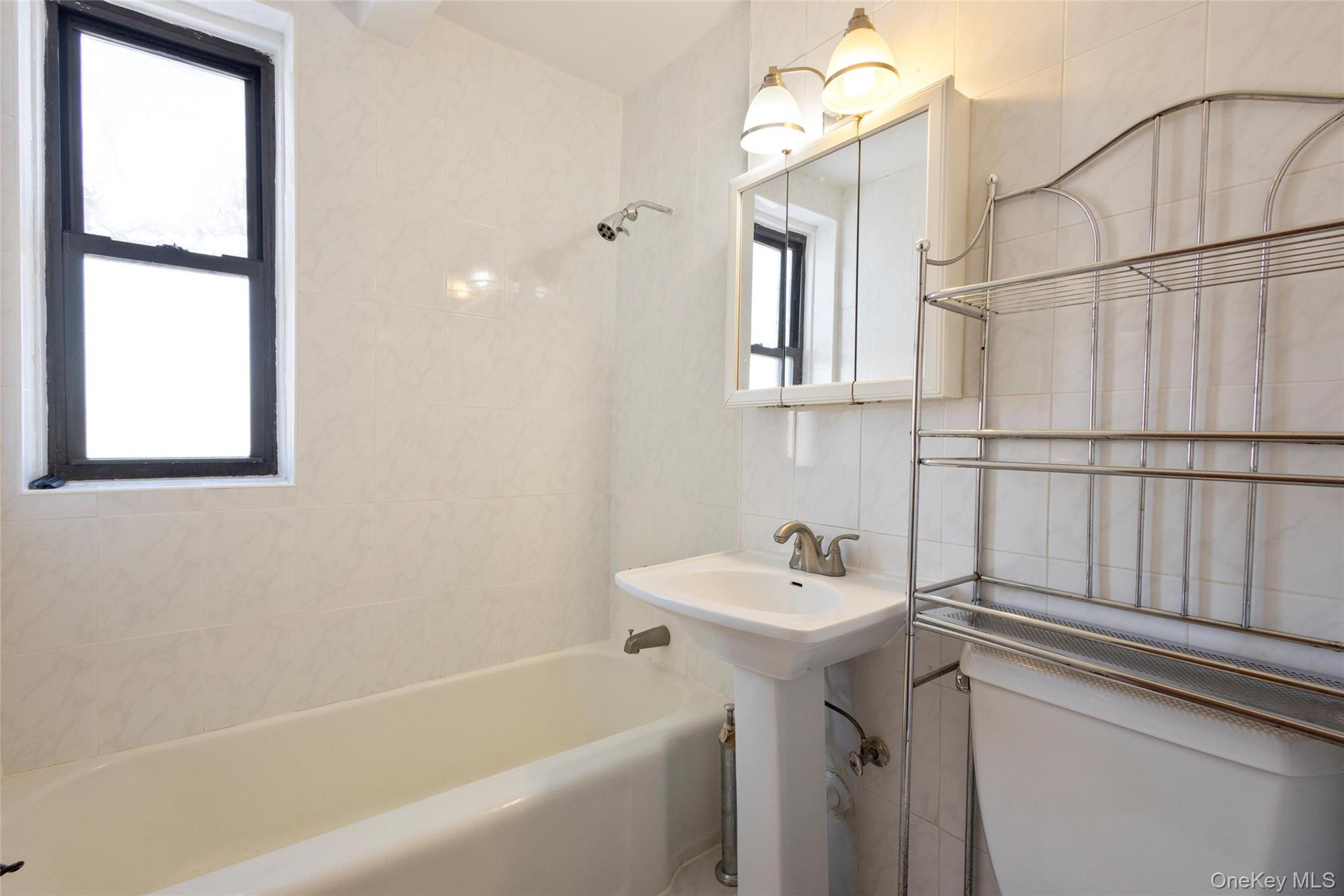 102-36 64th Avenue, Unit 6B Queens, NY 11375 - Photo 7 of 12 a bathroom with a sink a mirror and a bathtub