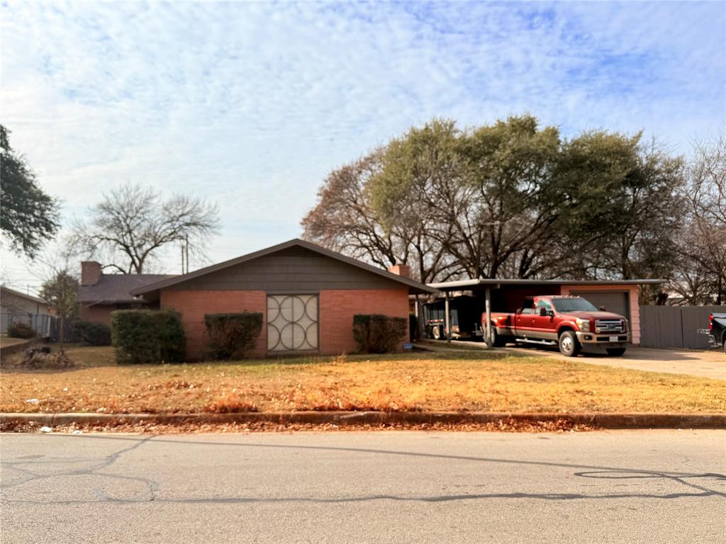 Single story home featuring driveway, a chimney, and brick siding