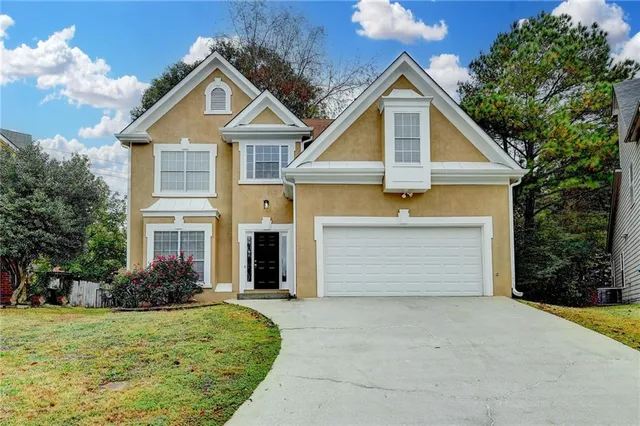a front view of a house with a garden and garage