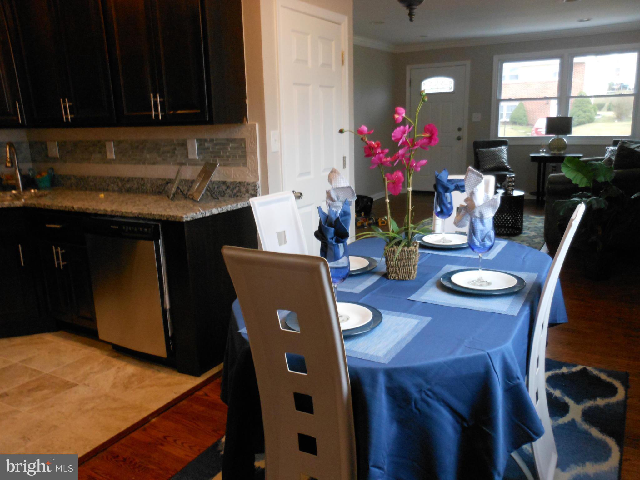 7302 Dooman Road Baltimore, MD 21244 - Photo 7 of 29 a kitchen with stainless steel appliances granite countertop a stove a sink a dining table and chairs