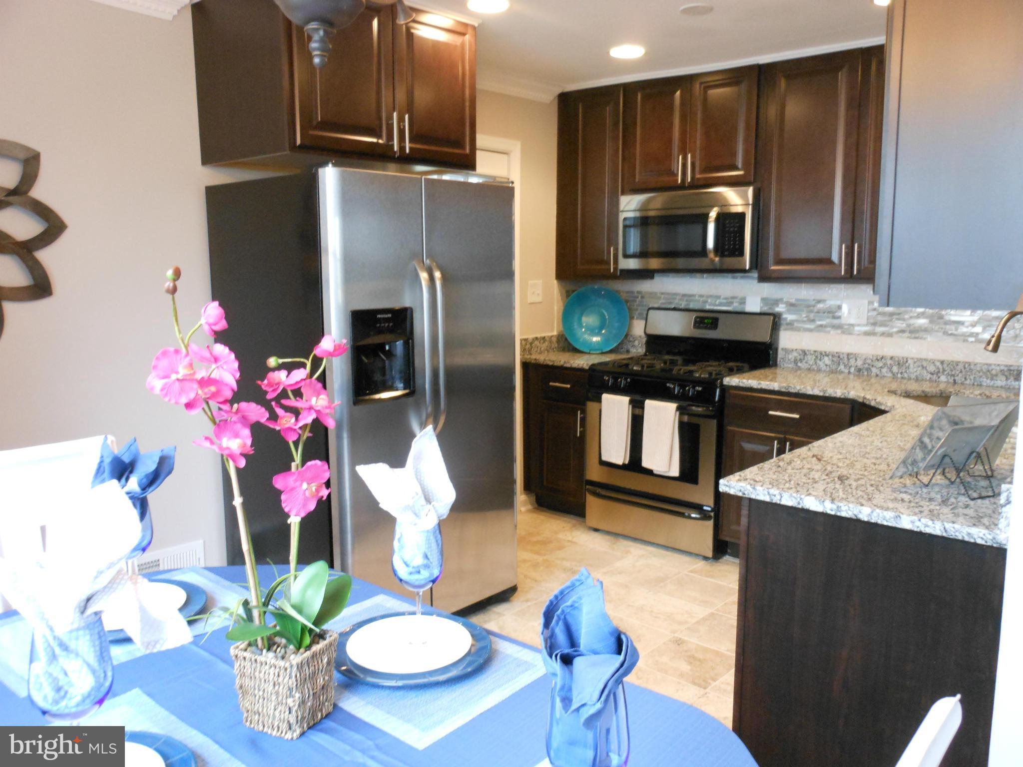 7302 Dooman Road Baltimore, MD 21244 - Photo 8 of 29 a kitchen with stainless steel appliances kitchen island granite countertop a refrigerator a stove top oven a sink and dishwasher