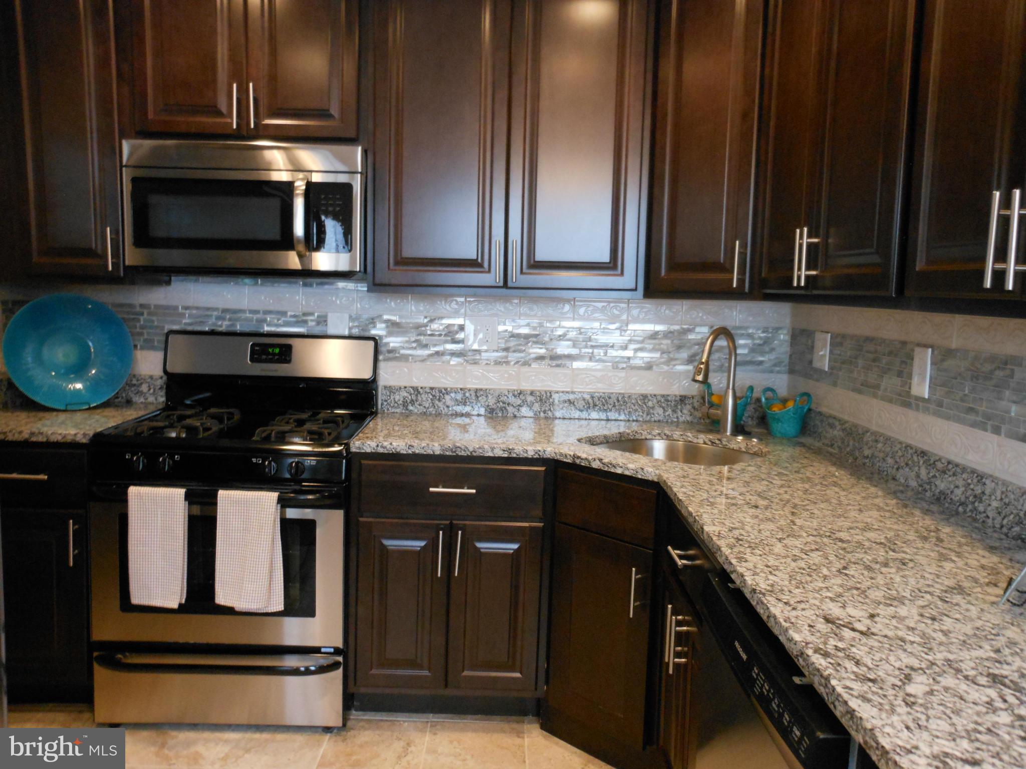 7302 Dooman Road Baltimore, MD 21244 - Photo 9 of 29 a kitchen with stainless steel appliances granite countertop a stove and a microwave