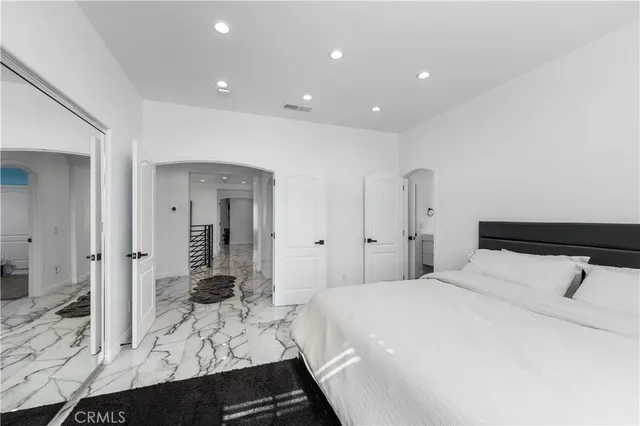 a spacious bedroom with a bed and a flat tv screen