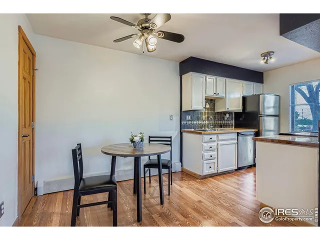 a kitchen with stainless steel appliances kitchen island granite countertop a dining table chairs and a refrigerator