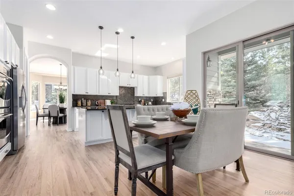 a kitchen with kitchen island granite countertop a dining table chairs refrigerator and cabinets