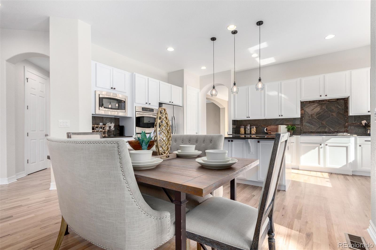 20166 East Shady Ridge Road Parker, CO 80134 - Photo 14 of 50 a kitchen with kitchen island granite countertop a dining table chairs refrigerator and cabinets
