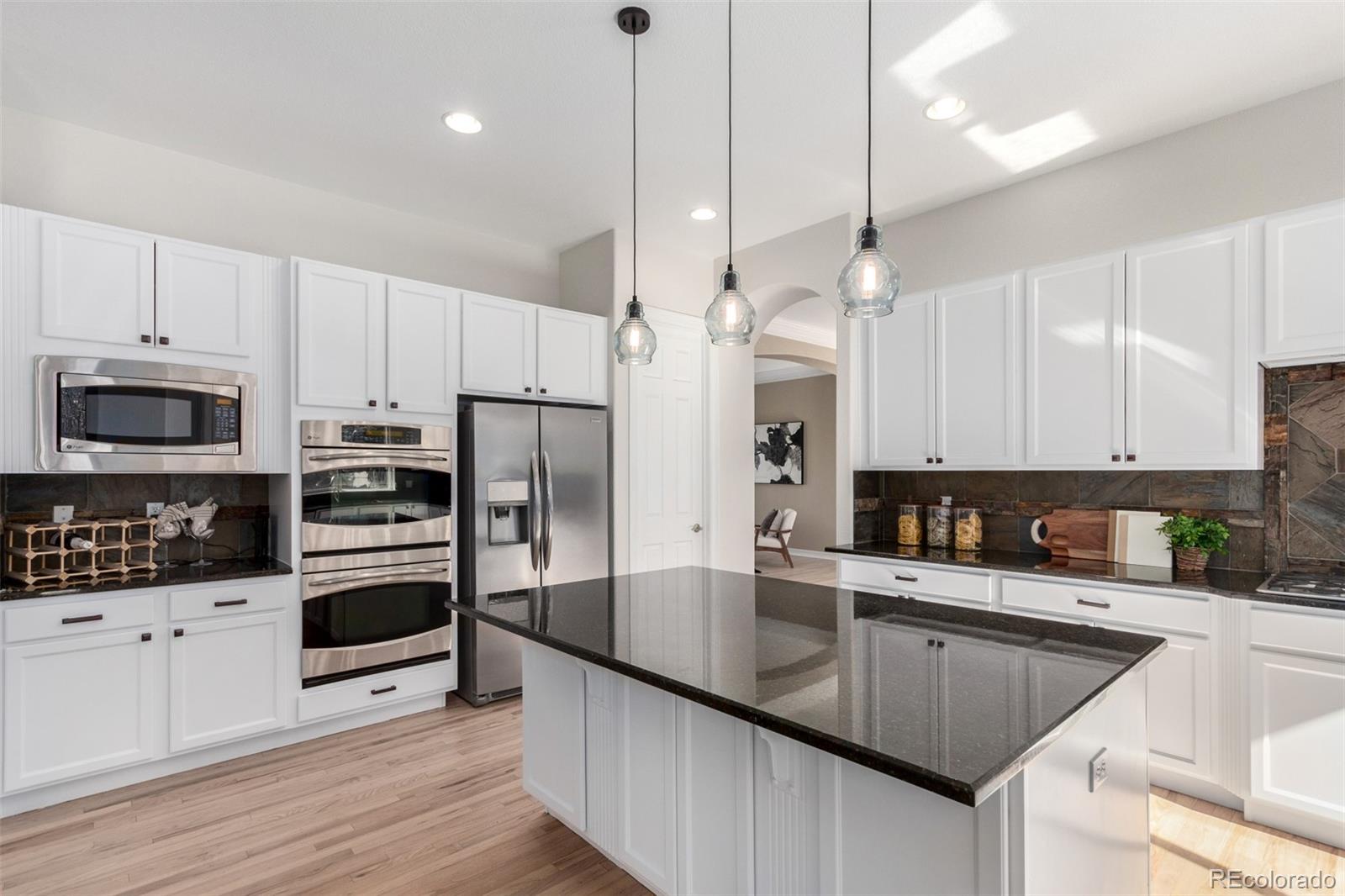 20166 East Shady Ridge Road Parker, CO 80134 - Photo 15 of 50 a kitchen with stainless steel appliances granite countertop a sink a stove a refrigerator and island with wooden floor