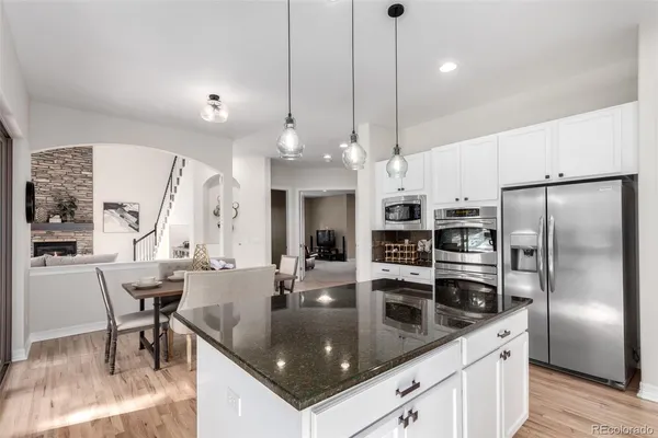 a kitchen with kitchen island granite countertop a sink a counter top space appliances and cabinets