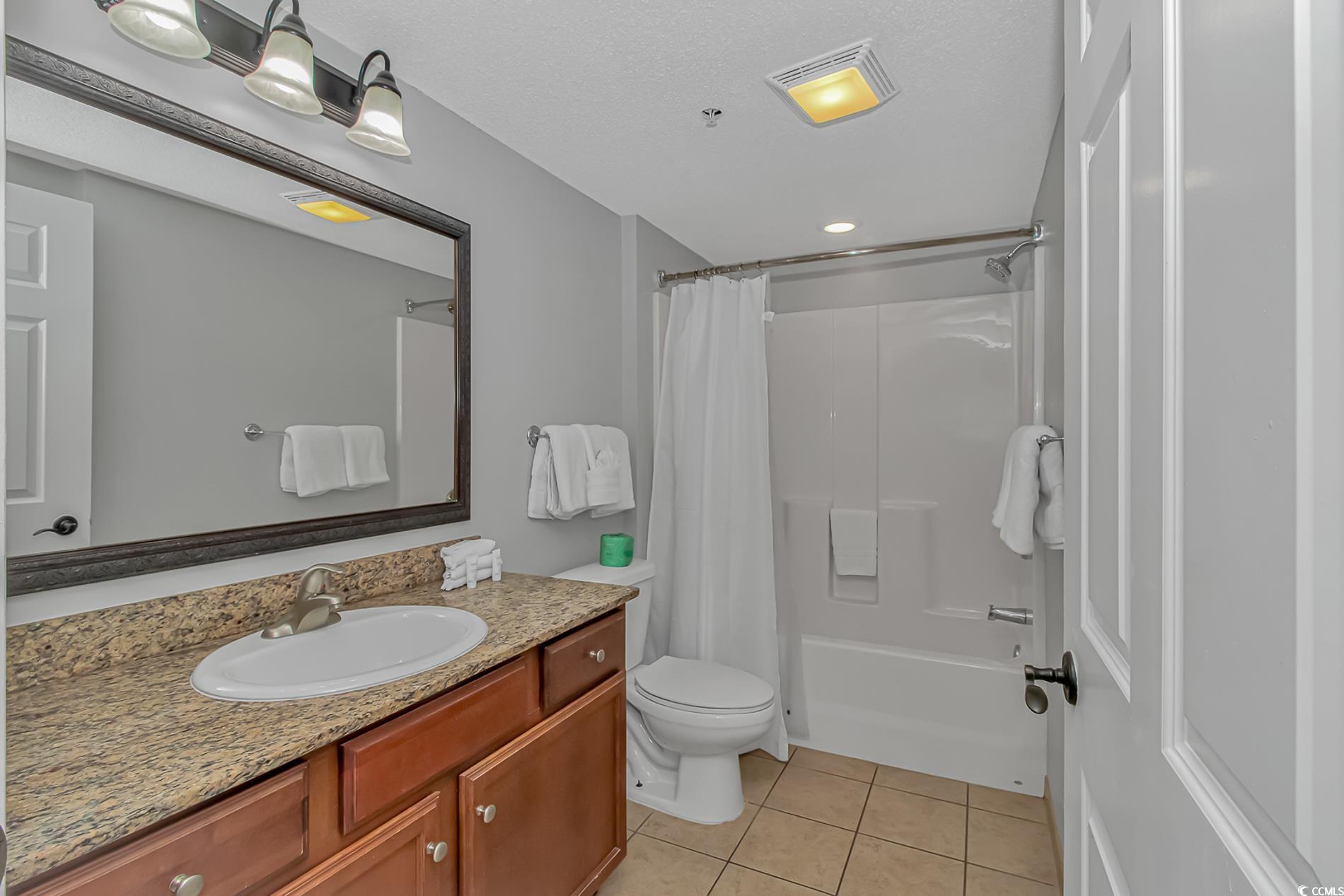 2600 North Ocean Boulevard, Unit 1715 Myrtle Beach, SC 29577 - Photo 10 of 34 Bathroom featuring shower / tub combo with curtain, vanity, and light tile patterned flooring