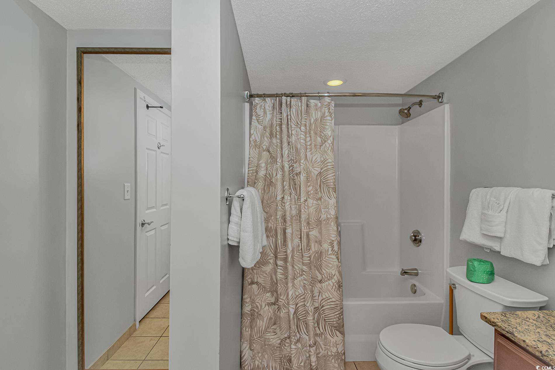 2600 North Ocean Boulevard, Unit 1715 Myrtle Beach, SC 29577 - Photo 18 of 34 Bathroom with a textured ceiling, shower / bathtub combination with curtain, vanity, and light tile patterned floors