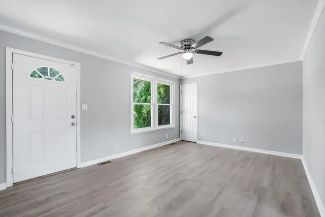 a view of an empty room with a window and wooden floor