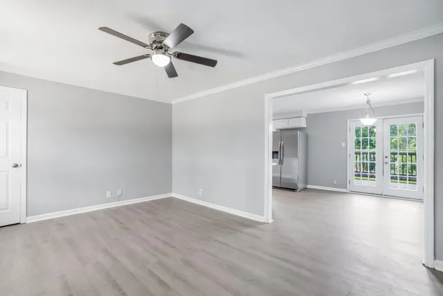 a view of an empty room with wooden floor and a ceiling fan