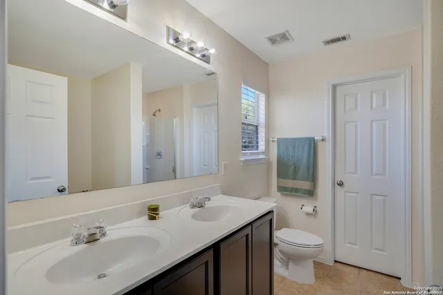 a bathroom with a toilet a sink a mirror a window and vanity