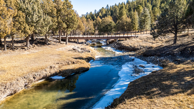 1955 West Mammoth Crk Road Hatch, UT 84735 - Photo 4 of 52 Natural landscape featuring a river with partial ice cover, a wooden pedestrian bridge, and surrounding evergreen trees