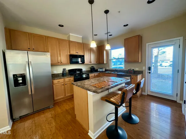 a kitchen with kitchen island a refrigerator a stove a sink and a island