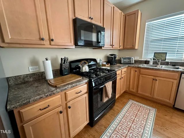 a kitchen with granite countertop stainless steel appliances a stove a sink and cabinets
