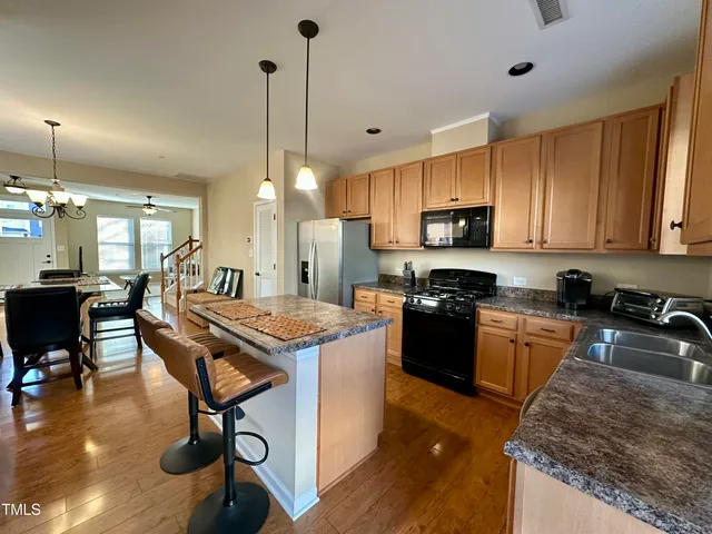a kitchen with granite countertop kitchen island stainless steel appliances a stove a sink a oven a dining table and chairs