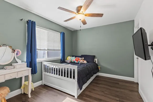 a view of a hallway with wooden floor and a flat screen tv