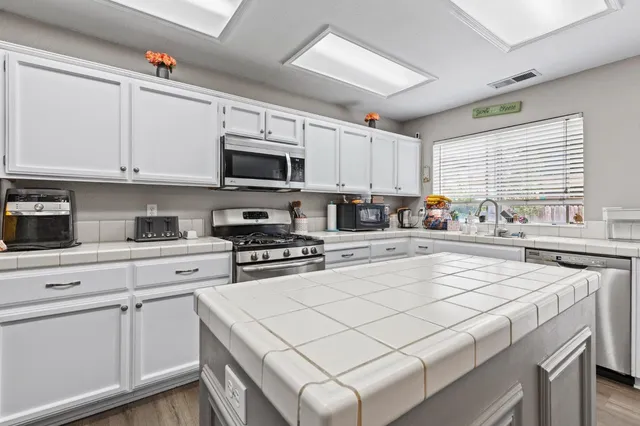 a kitchen with stainless steel appliances a sink a window and cabinets