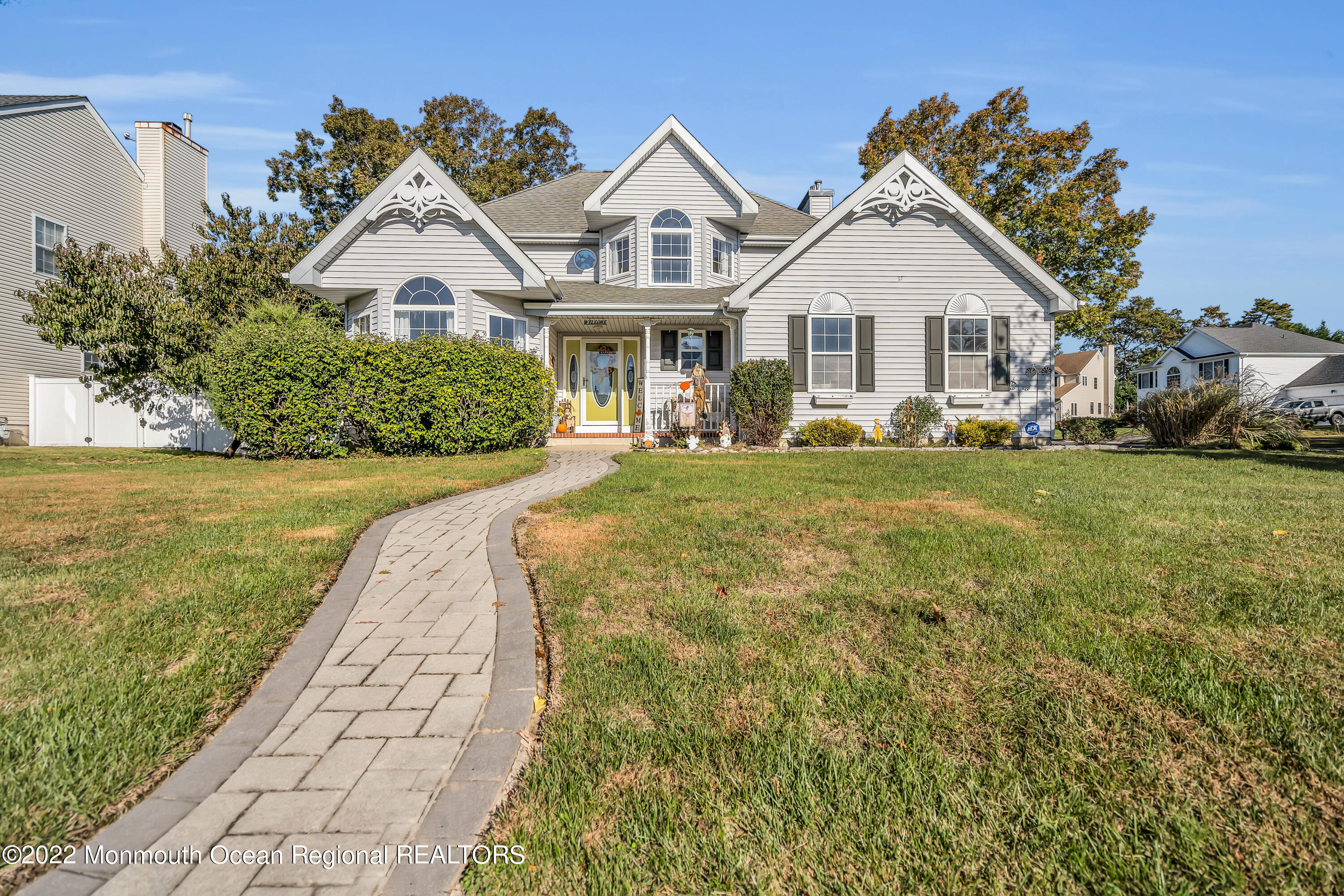 124 Compass Road Manahawkin, NJ 08050 - Photo 36 of 36 a view of a white house with a yard and table and chairs under an umbrella