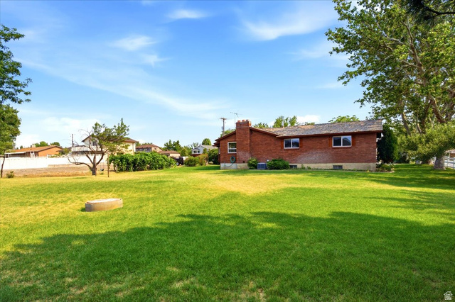 2252 West 800 North Clinton, UT 84015 - Photo 29 of 38 Expansive green lawn with mature trees and a concrete ring