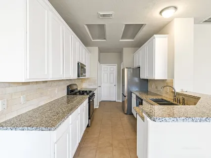 a kitchen with granite countertop a sink a counter top space and cabinets