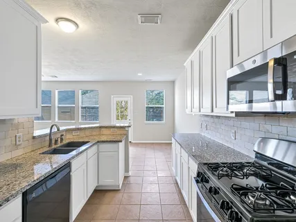 a kitchen with granite countertop a sink stove and cabinets