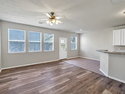 a view of an empty room with a window and wooden floor