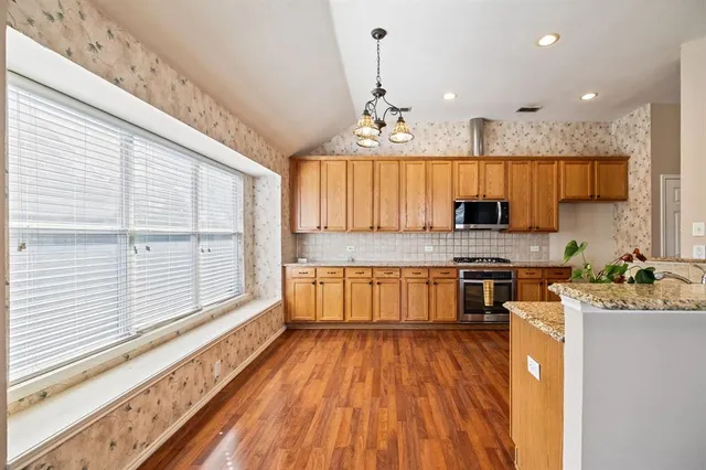 a kitchen with stainless steel appliances granite countertop a stove and a wooden floors