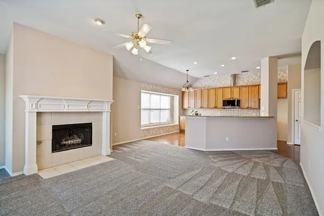 a view of kitchen and empty room with fireplace